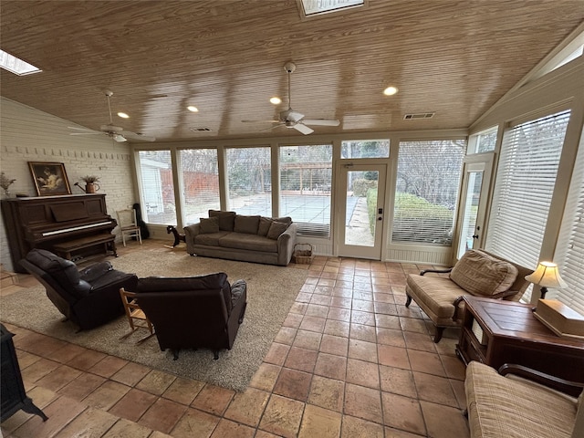 interior space with lofted ceiling with skylight, wooden ceiling, ceiling fan, and brick wall