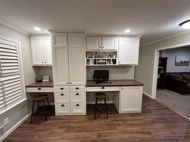 office featuring dark wood-type flooring, ornamental molding, and built in desk