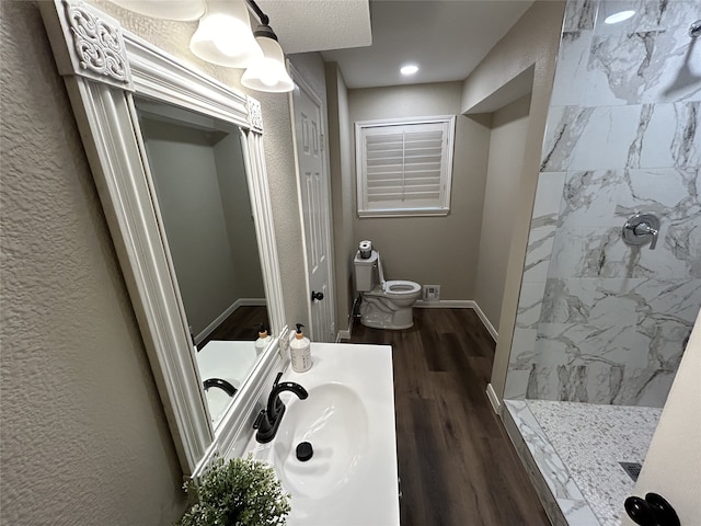 bathroom with toilet, hardwood / wood-style floors, vanity, and walk in shower