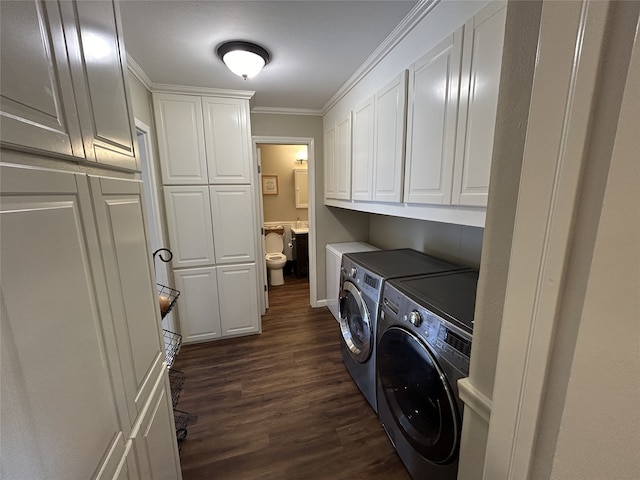 clothes washing area featuring cabinets, ornamental molding, dark hardwood / wood-style flooring, and washing machine and dryer