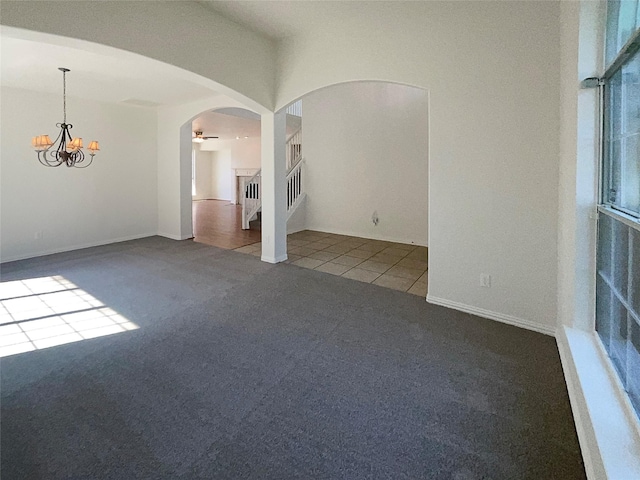 carpeted empty room featuring an inviting chandelier