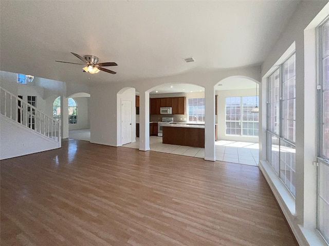 unfurnished living room with ceiling fan, sink, and hardwood / wood-style floors