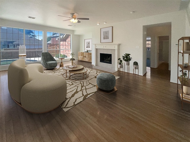 living room featuring a tiled fireplace, dark hardwood / wood-style floors, and ceiling fan