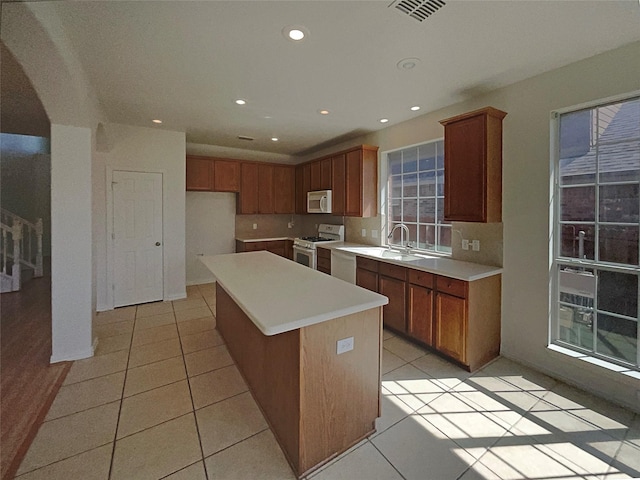 kitchen with white appliances, sink, a kitchen island, and light tile patterned floors