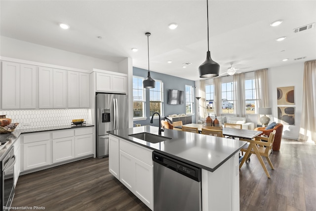 kitchen with white cabinets, appliances with stainless steel finishes, decorative light fixtures, decorative backsplash, and sink