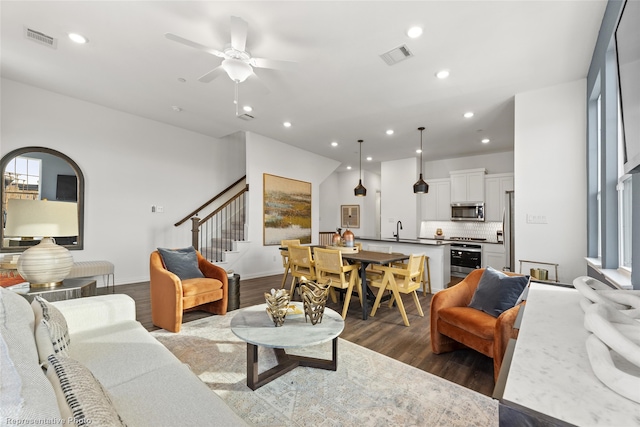 living room featuring sink, dark wood-type flooring, and ceiling fan