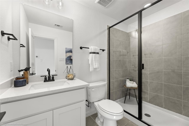 bathroom featuring tile patterned flooring, toilet, a shower with door, and vanity