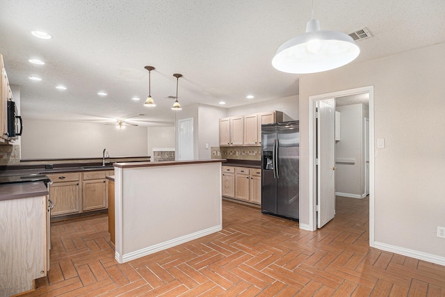 kitchen featuring light brown cabinetry, decorative backsplash, sink, decorative light fixtures, and stainless steel fridge