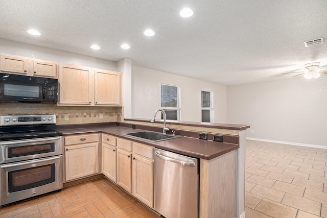 kitchen with a textured ceiling, appliances with stainless steel finishes, decorative backsplash, sink, and kitchen peninsula