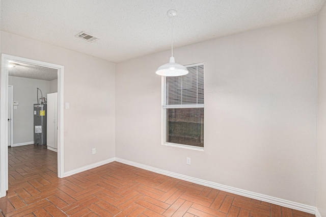 spare room featuring a textured ceiling and electric water heater