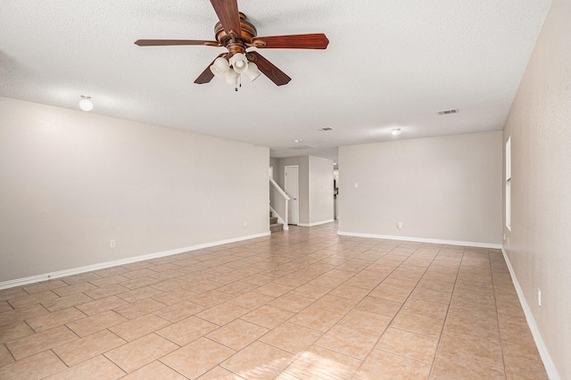 tiled spare room featuring a textured ceiling and ceiling fan