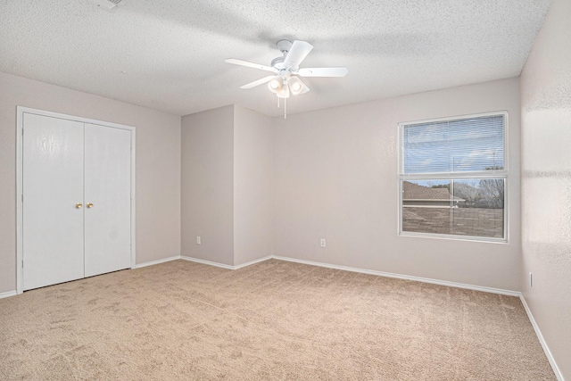 unfurnished bedroom featuring light carpet, a textured ceiling, a closet, and ceiling fan