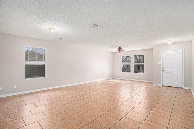 empty room with a textured ceiling, light tile patterned floors, and ceiling fan