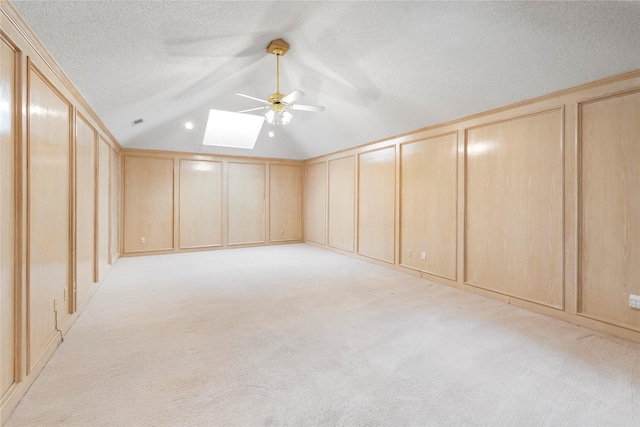 bonus room with a textured ceiling, light colored carpet, ceiling fan, and lofted ceiling with skylight