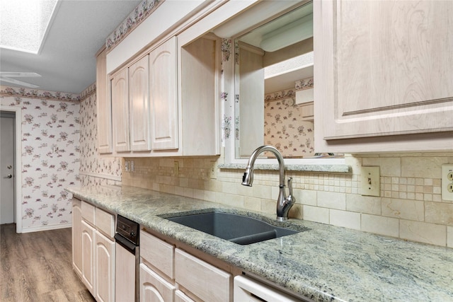 kitchen featuring light stone countertops, light brown cabinets, sink, backsplash, and light hardwood / wood-style flooring