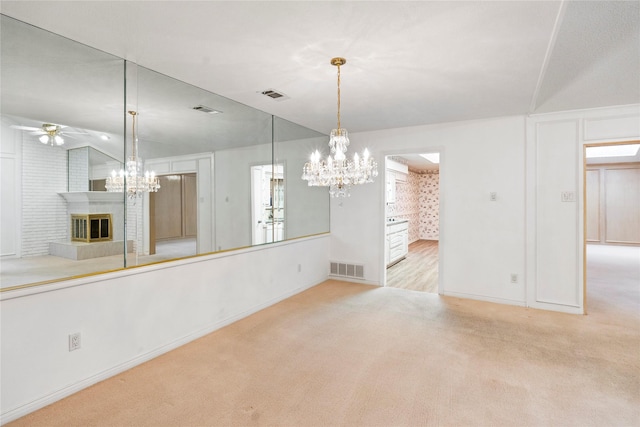 interior space with ceiling fan with notable chandelier, light colored carpet, vaulted ceiling, and a brick fireplace