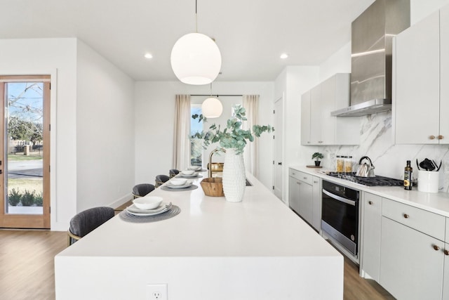 kitchen featuring pendant lighting, a center island, wall chimney exhaust hood, and appliances with stainless steel finishes