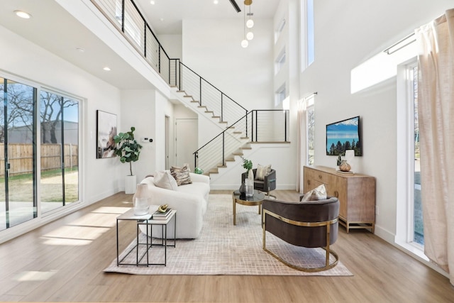 living room featuring light wood-type flooring and a towering ceiling