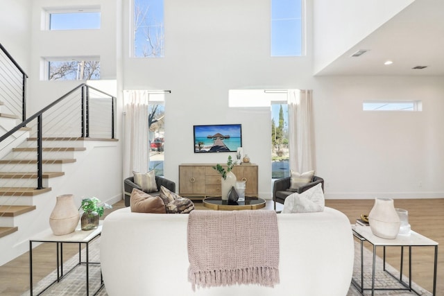 living room featuring light hardwood / wood-style floors, a high ceiling, and a wealth of natural light