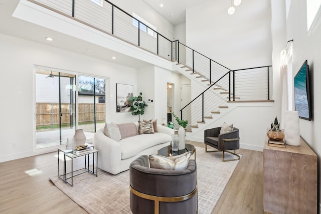 living room with light wood-type flooring and a towering ceiling