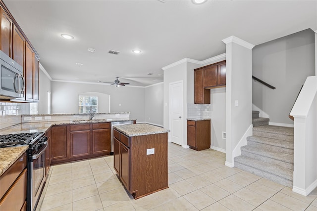 kitchen featuring visible vents, a kitchen island, light stone countertops, stainless steel appliances, and light tile patterned flooring