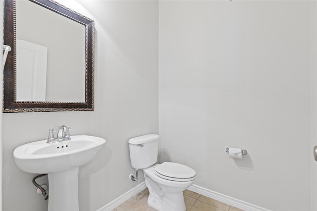 half bath with toilet, tile patterned flooring, and baseboards