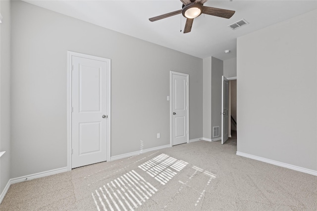 unfurnished bedroom with light carpet, a ceiling fan, visible vents, and baseboards