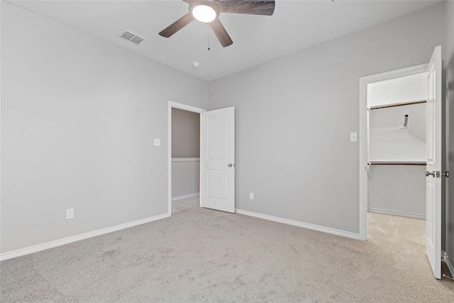 unfurnished bedroom with light carpet, a spacious closet, visible vents, and baseboards