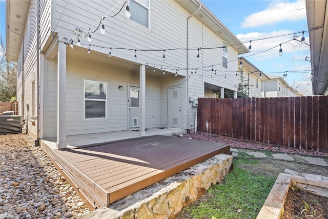 rear view of property with fence, a wooden deck, and central AC unit