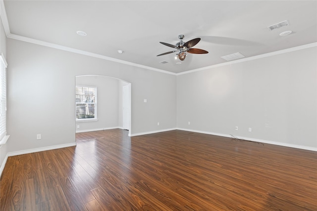 spare room featuring arched walkways, dark wood-type flooring, visible vents, and baseboards