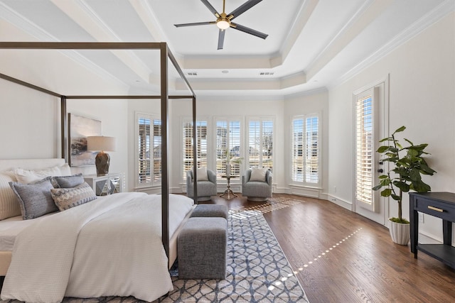 bedroom with hardwood / wood-style floors, crown molding, a raised ceiling, and ceiling fan