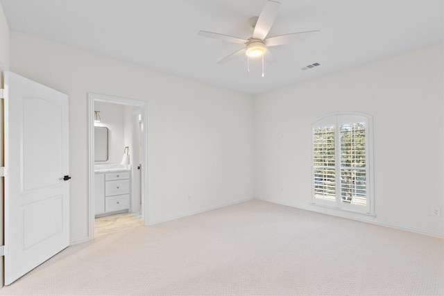 unfurnished bedroom featuring light carpet, ensuite bath, and ceiling fan