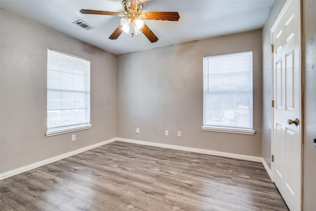 empty room featuring hardwood / wood-style flooring, a wealth of natural light, and ceiling fan