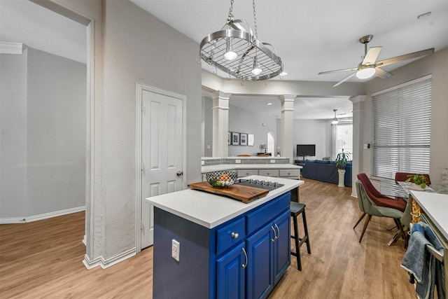 kitchen with pendant lighting, a center island, ornate columns, light hardwood / wood-style floors, and blue cabinetry