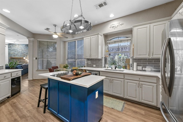 kitchen with a center island, light hardwood / wood-style floors, tasteful backsplash, sink, and stainless steel appliances