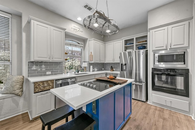 kitchen with black appliances, a center island, decorative light fixtures, white cabinetry, and sink