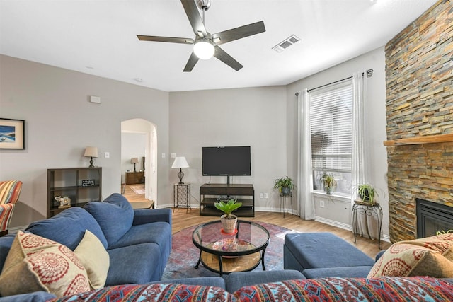 living room featuring a fireplace, light hardwood / wood-style flooring, and ceiling fan