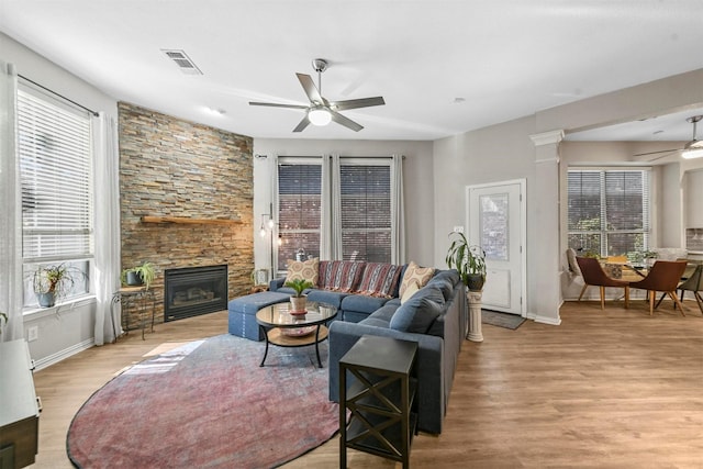 living room with a fireplace, light hardwood / wood-style floors, a wealth of natural light, and ceiling fan