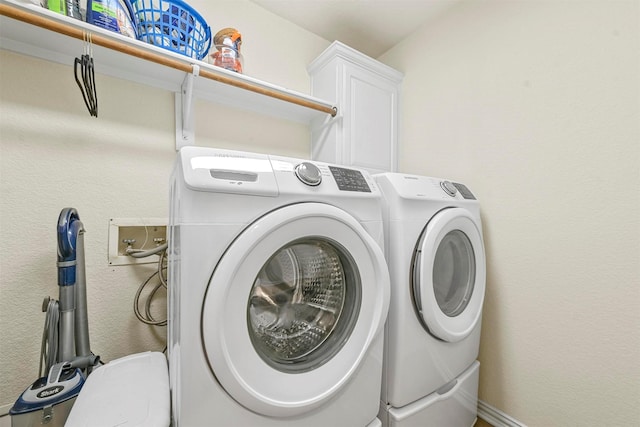 washroom with washer and clothes dryer and cabinets