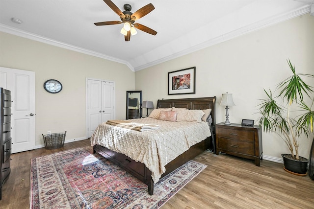 bedroom with wood-type flooring, crown molding, ceiling fan, a closet, and lofted ceiling