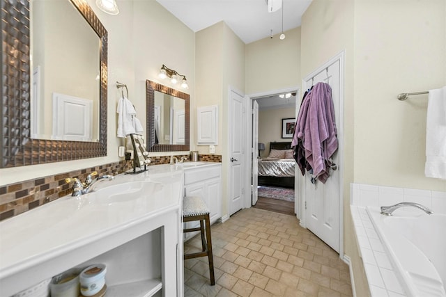 bathroom featuring tiled tub and vanity