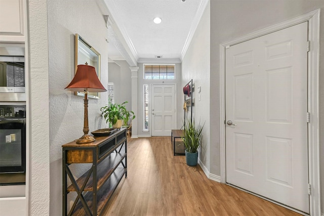 foyer featuring crown molding, light hardwood / wood-style flooring, and a textured ceiling