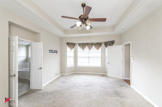 empty room featuring light carpet, ceiling fan, and a raised ceiling