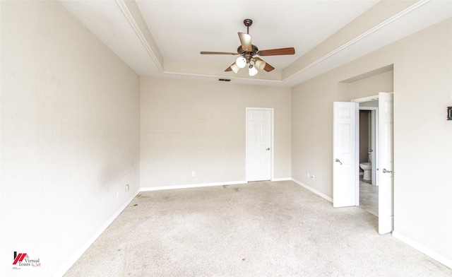 spare room featuring ceiling fan, light carpet, and a tray ceiling