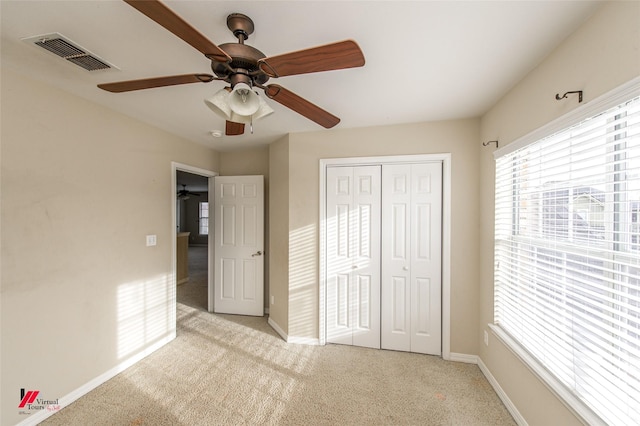 unfurnished bedroom featuring light carpet, a closet, and ceiling fan