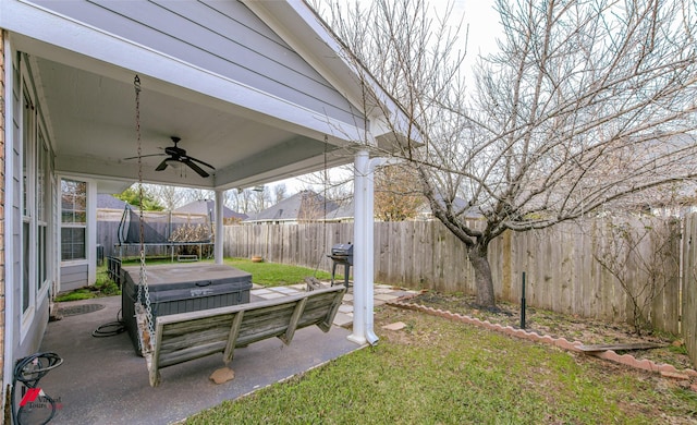 view of yard featuring ceiling fan, a trampoline, a patio area, and a hot tub