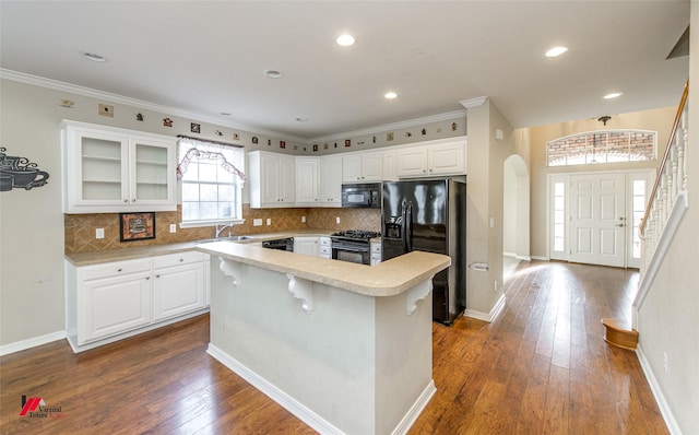 kitchen with decorative backsplash, white cabinets, black appliances, and a kitchen island