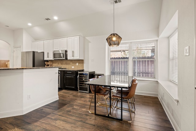 kitchen featuring dark stone counters, dark hardwood / wood-style flooring, stainless steel appliances, beverage cooler, and white cabinets