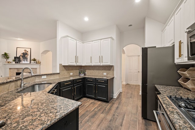 kitchen with sink, white cabinetry, hardwood / wood-style floors, decorative backsplash, and dark stone counters