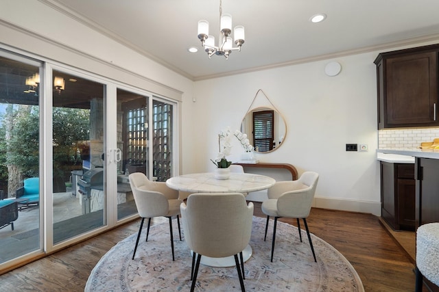 dining space featuring dark hardwood / wood-style floors, ornamental molding, and a notable chandelier